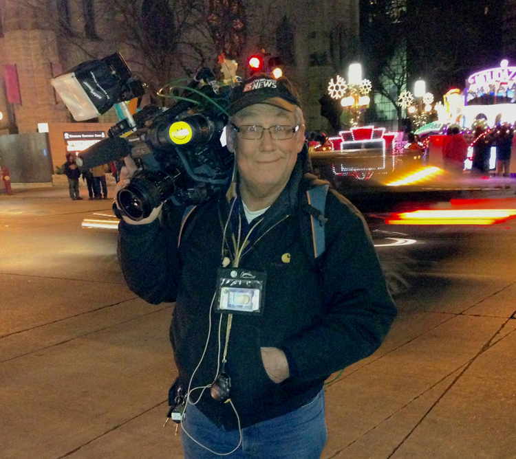 Older man standing in front of a park holding a new broadcasting camera
