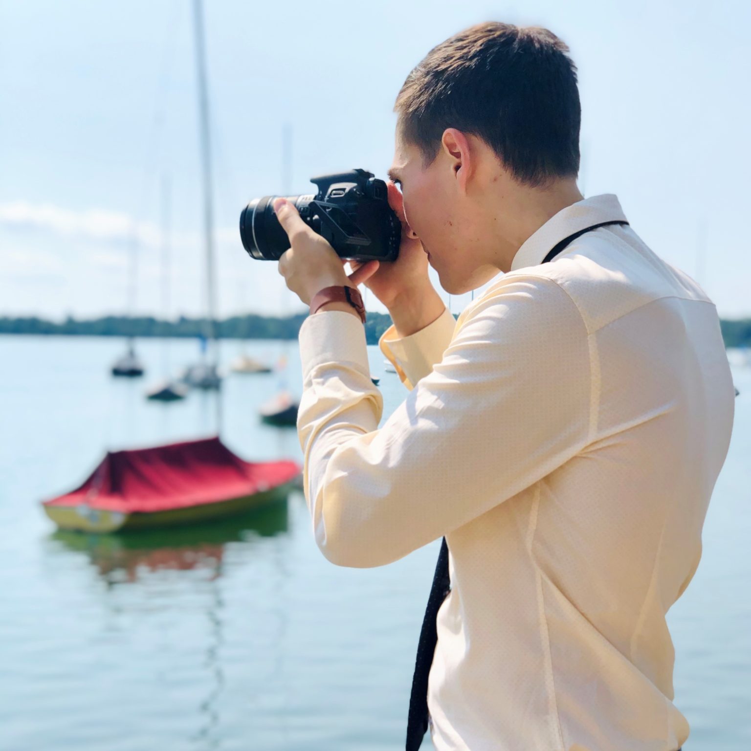 A man holding a camera taking a photo of a lake