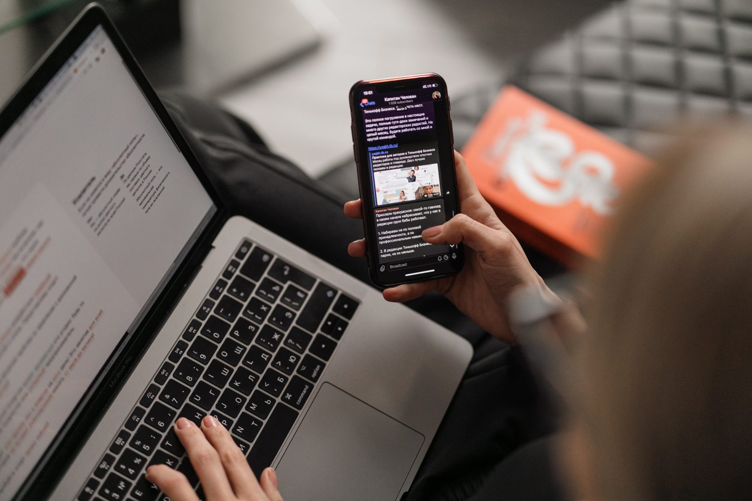 One hand typing on a cell phone and the other hand typing on a computer