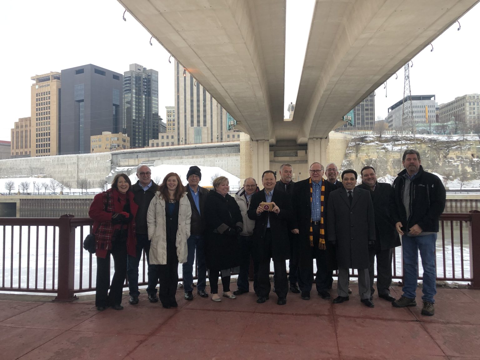 Group standing under a bridge with tall buildings in the background