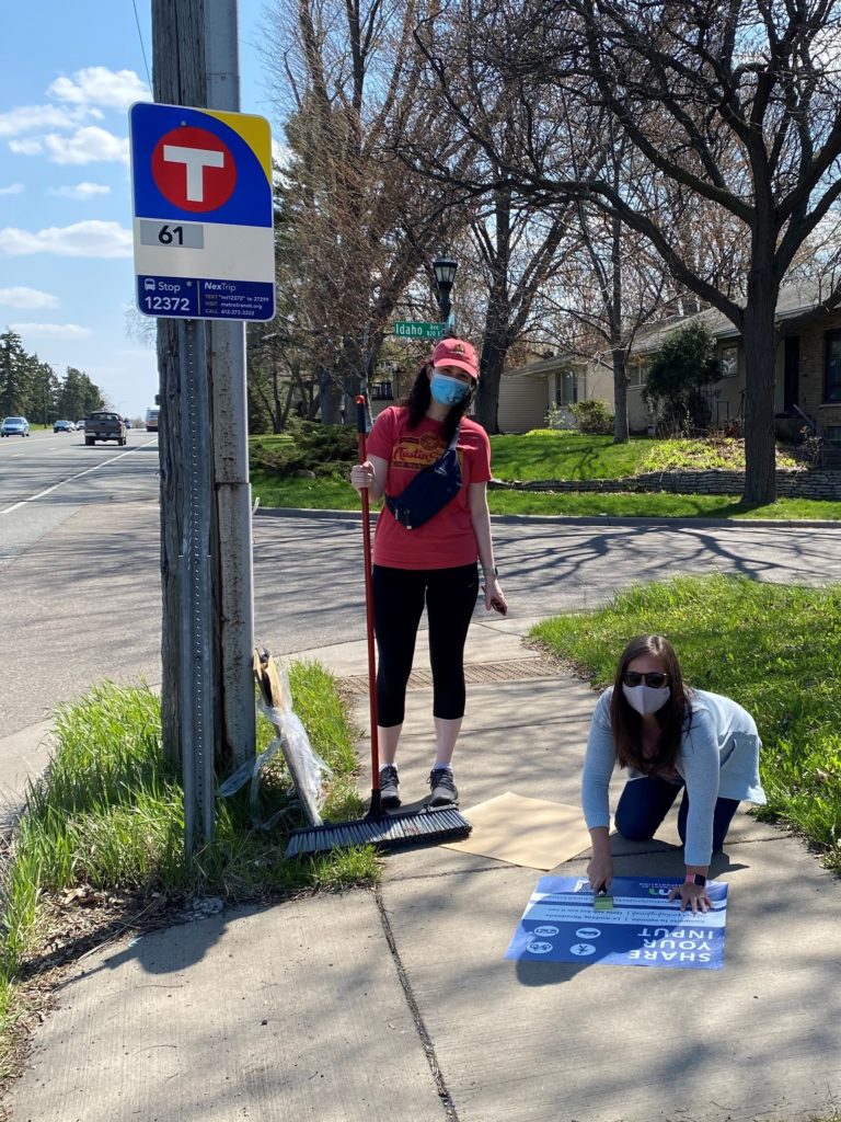 Two women handing up signs on the corner of a sidewalk