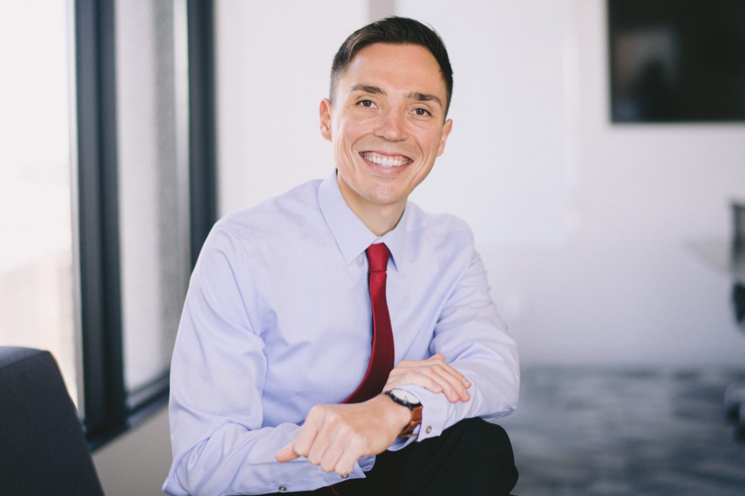 A close-up headshot of a man smiling and wearing business attire