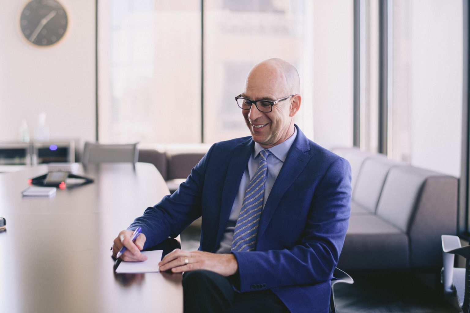 Close-up of a man smiling and wearing a suit and writing in a notepad