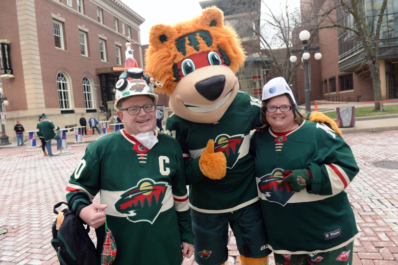 Two people standing with the Minnesota Wild hockey team's mascot