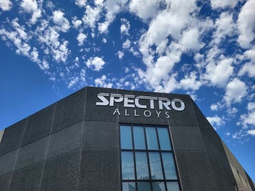 The top of a Spectro Alloys building entrance showing the sky and clouds above it