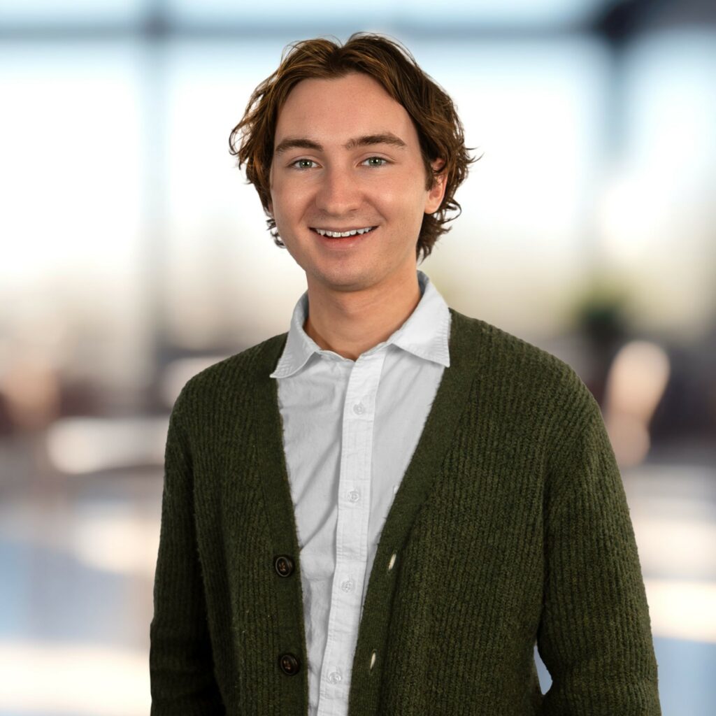 A young man wearing a button down and a green cardigan