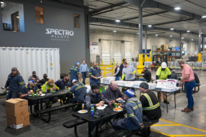 A group of employees eating lunch in a warehoiuse. 