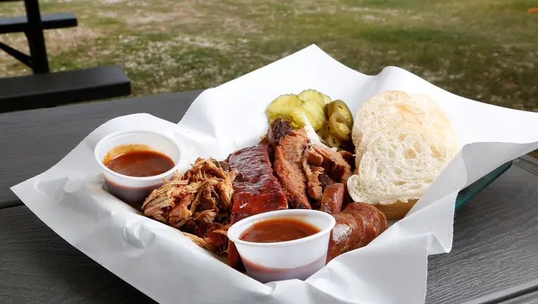 A plate of ribs with barbecue sauce and bread and pickles