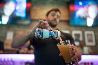 A bartender pours a Modist beer into a glass