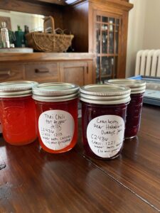 Four jars of various types of jams on a dining room table.