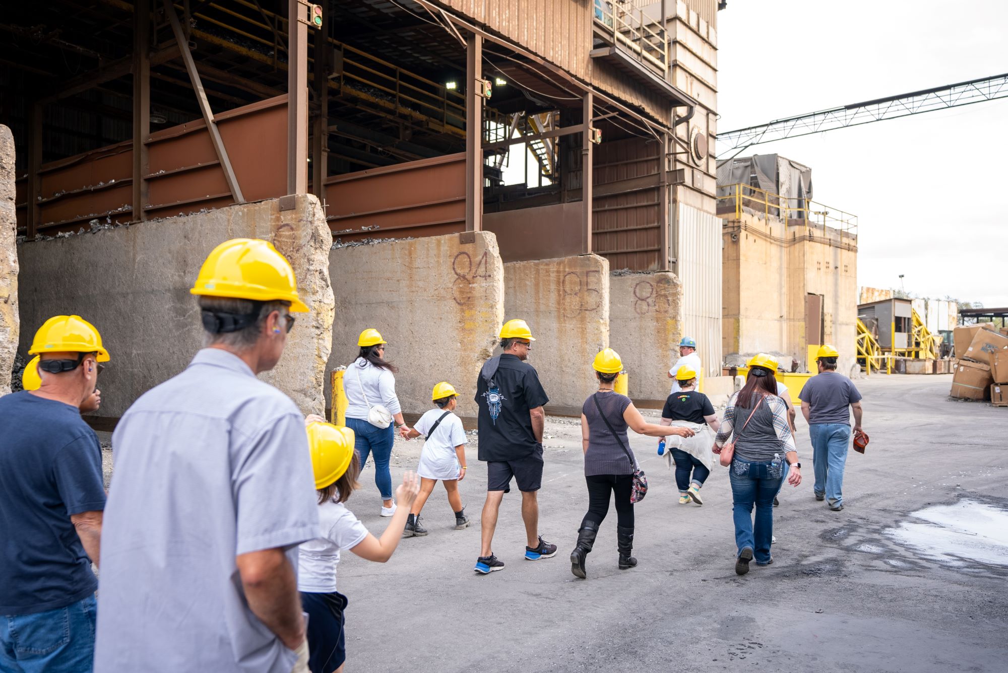 A group of people in hardhats walk through an industrial area.