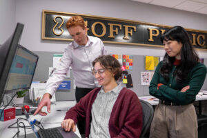 Three professionals looking at a computer screen. 