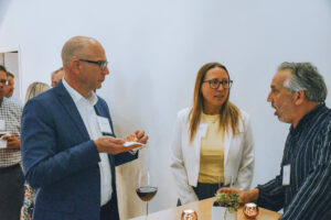 Three professionals talk at a party.