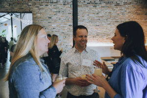 Three professionals talk at a party.