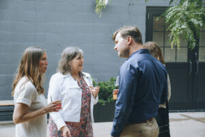 Three professionals talk at a party.