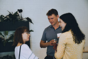 Three professionals talk at a party.