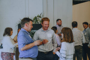 Three professionals talk at a party.