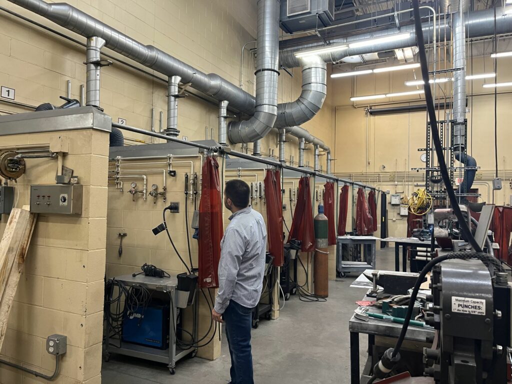 A man in a white button down shirt looks at air ventilation systems in a shop