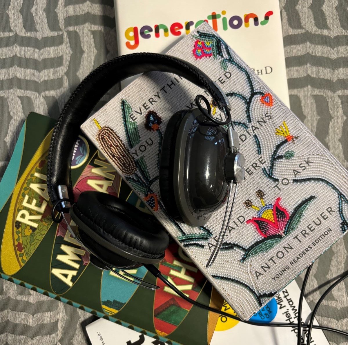 A pair of headphones sitting atop a pile of three books