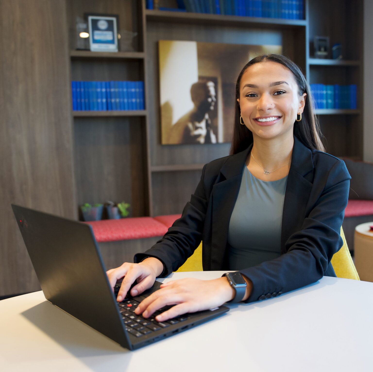 A young woman smiles while typing on a laptop