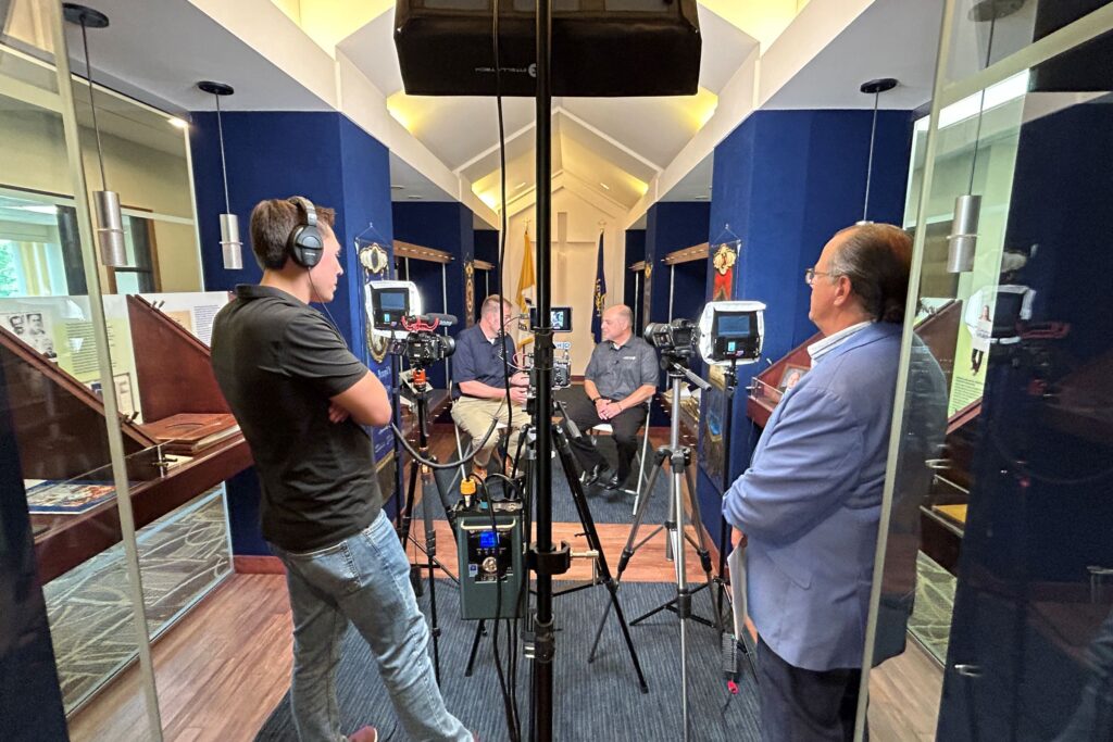 Goff Public team members stand behind the camera while interviewing two people