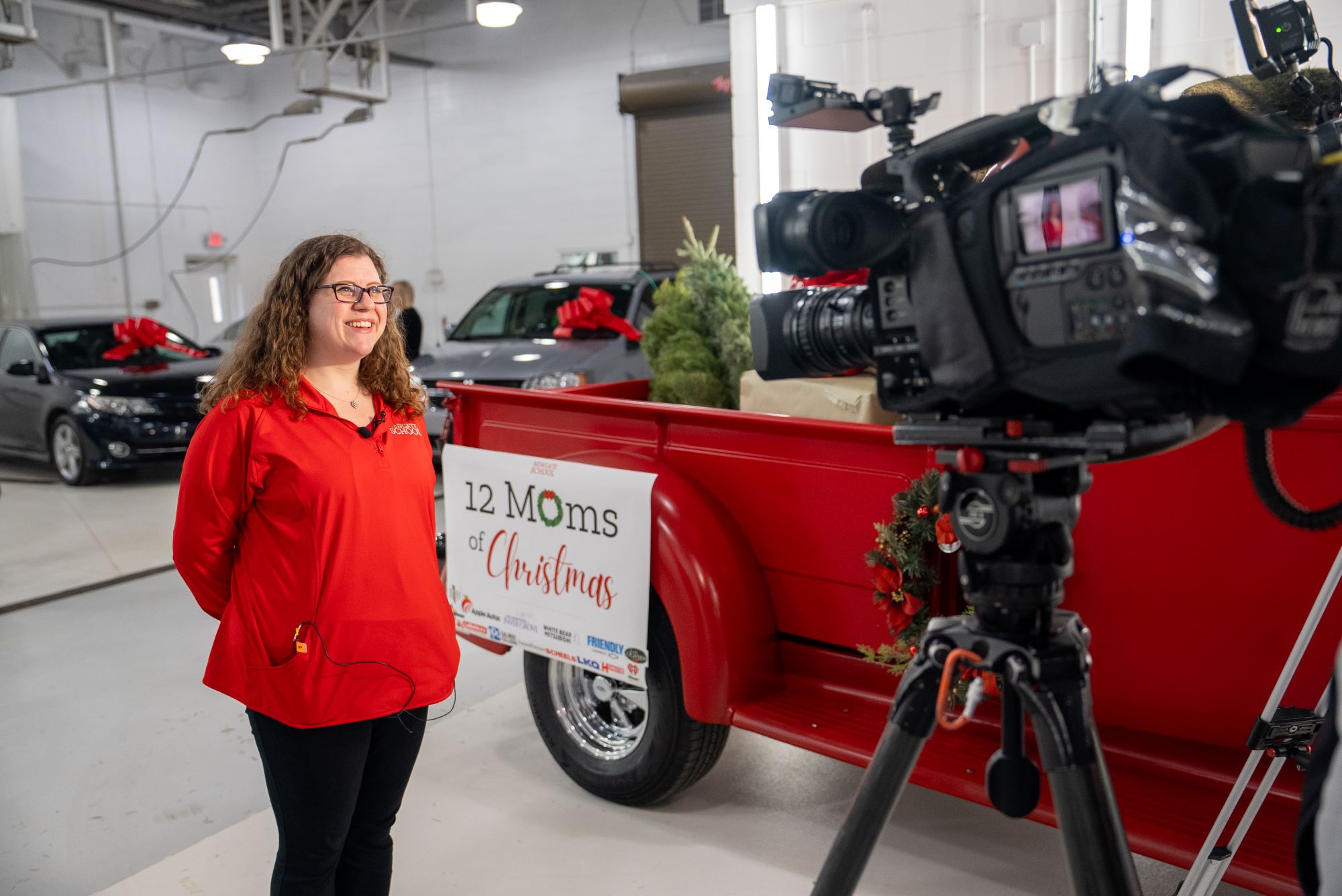 A women is interviewed in front of a 12 Moms of Christmas sign