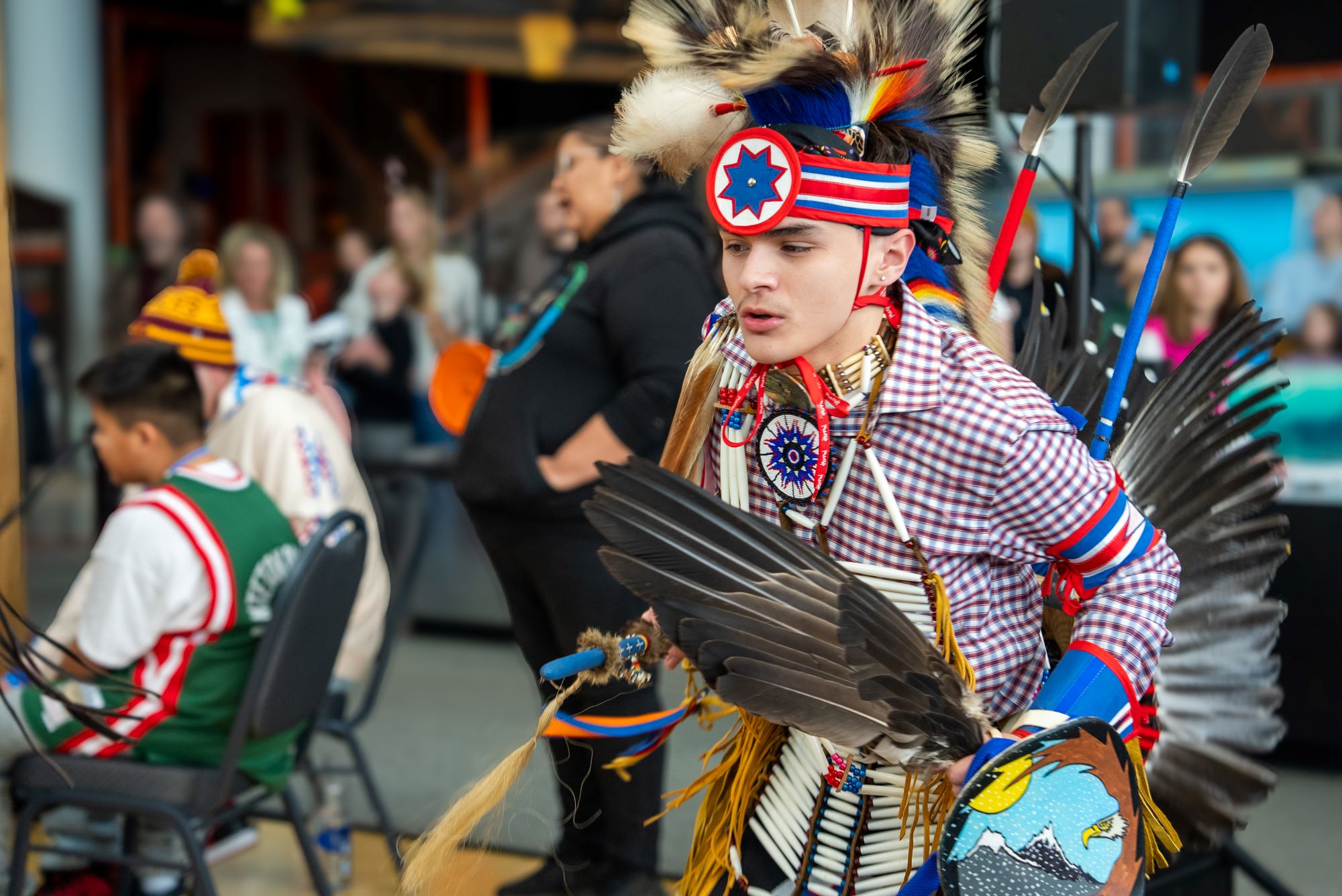 A young Native man dances in Indigenous garb