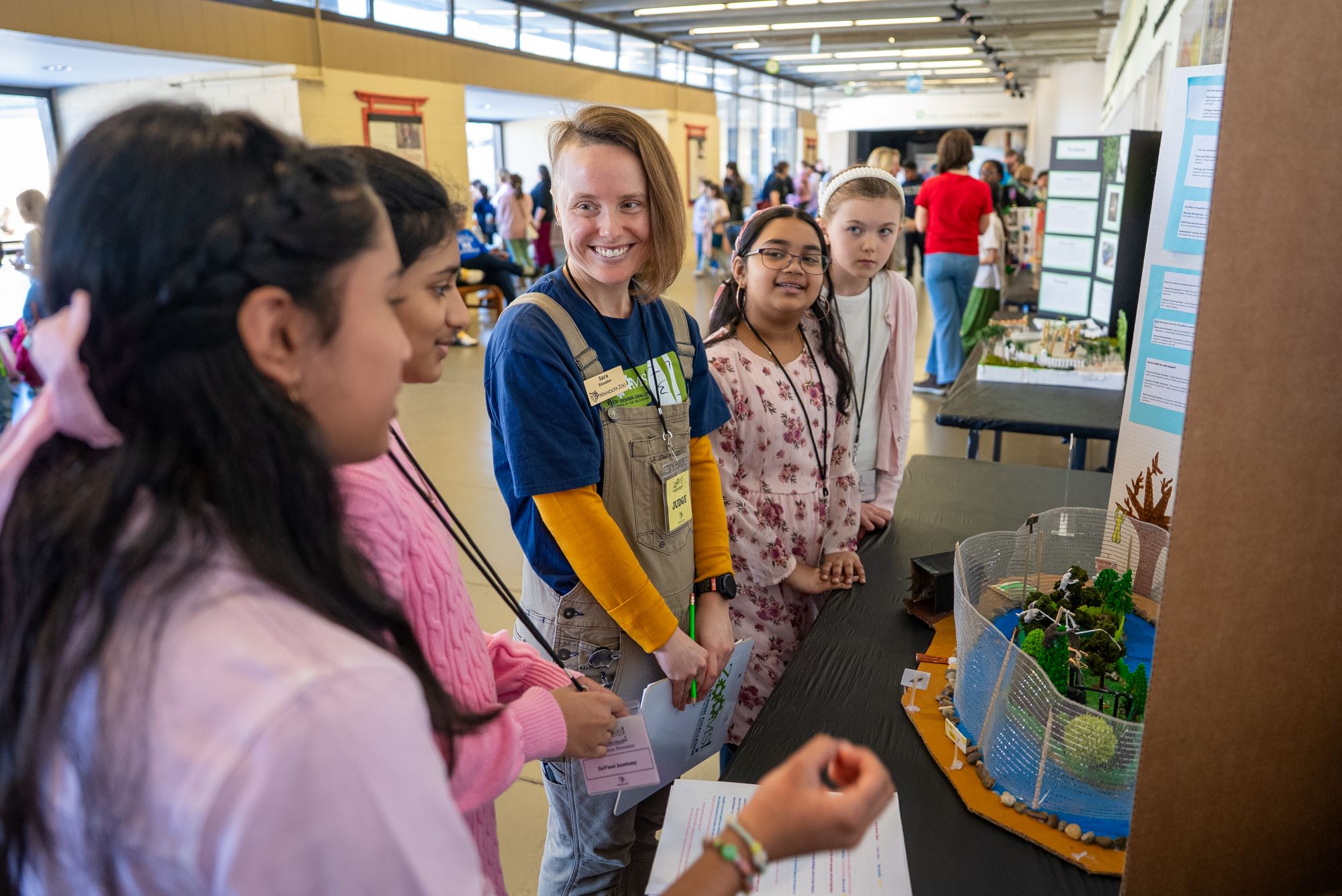 A group of people stand and chat around a science project