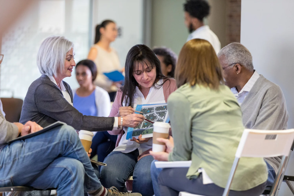 Three women and one man sitting in chairs looking at a map